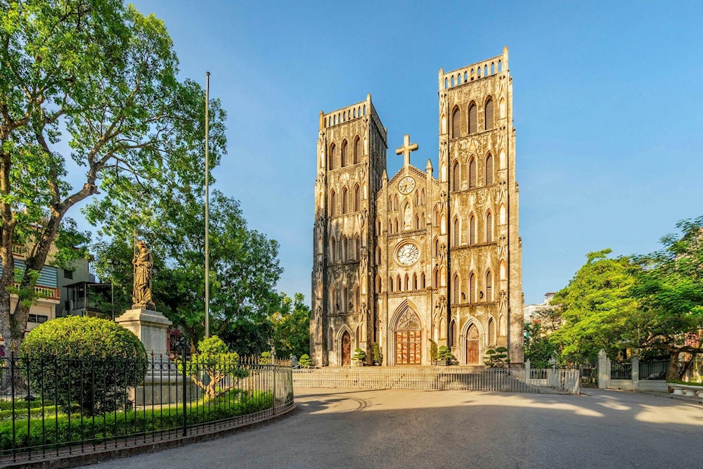 Hanoi St. Joseph Cathedral bathed in golden sunlight and framed by lush greenery
